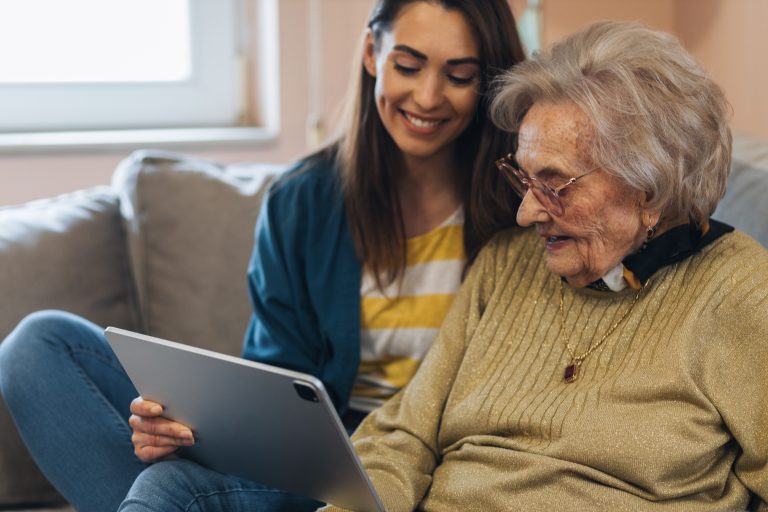 Nurse visiting a senior woman, showing her news online.